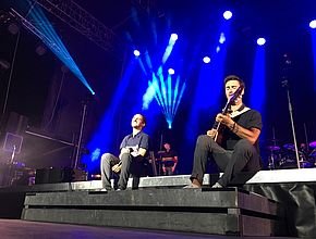 Assis sur une estrade, les musiciens de Boulevard des Airs jouent et chantent. - Agrandir l'image (fenêtre modale)